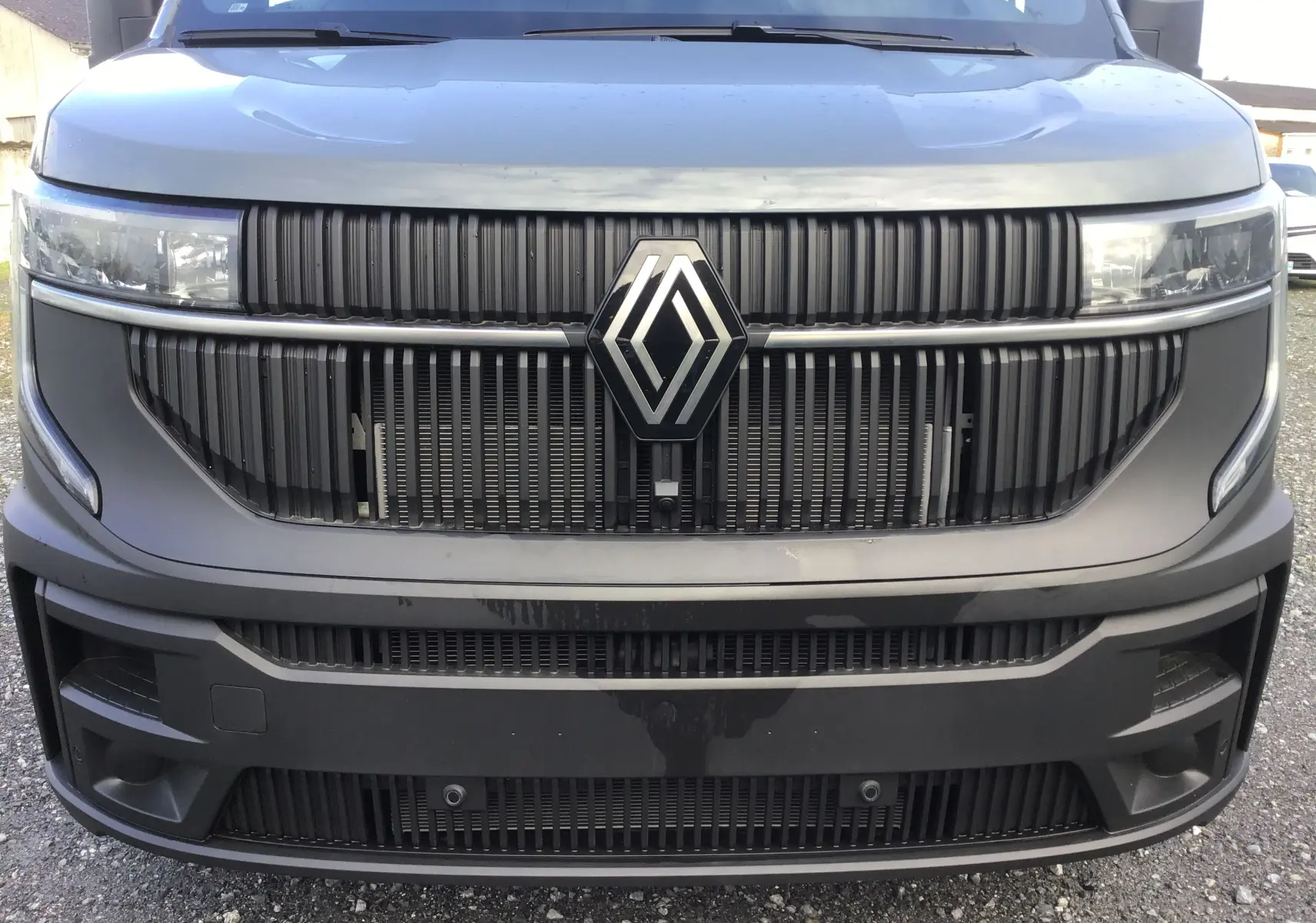 Vue frontale rapprochée du Renault Master gris urbain 2025 avec calandre noire et grand logo Renault central.