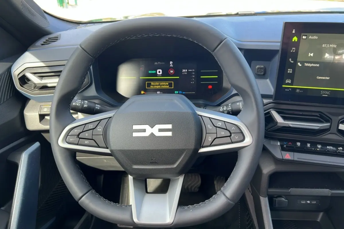 Vue intérieure centrée sur le volant cuir du Dacia Bigster Hybrid 155, avec tableau de bord numérique et écran tactile.