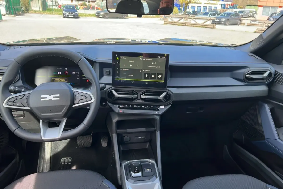 Vue intérieure du tableau de bord du Dacia Bigster 2026, avec volant cuir et écran tactile central noir.