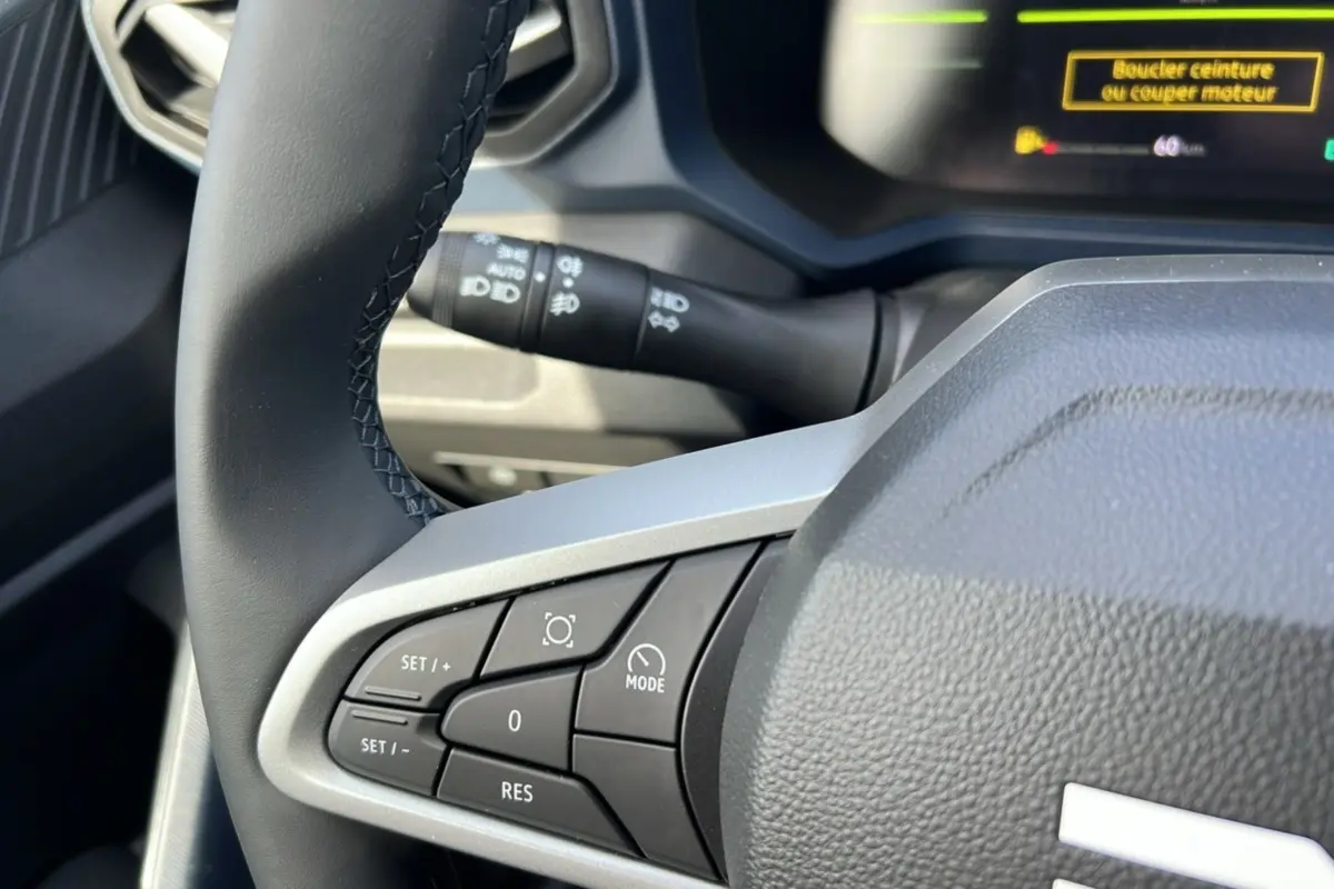 Gros plan sur le volant cuir noir du Dacia Bigster Hybrid 155 Expression Plus, avec commandes intégrées visibles.