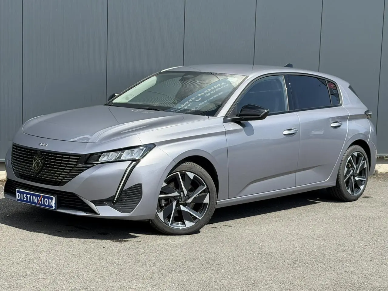 Peugeot 308 gris Artense vue 3/4 avant droit, avec jantes alliage 17'' et calandre noire brillante.