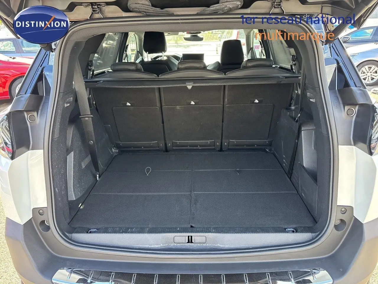 Coffre ouvert d’un Peugeot 5008 blanc nacré 2023, vue arrière montrant l’espace de chargement plat et les sièges rabattus.
