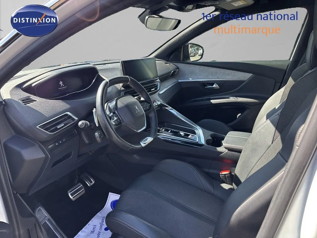 Vue intérieure côté conducteur du Peugeot 5008 blanc nacré 2023, avec tableau de bord moderne et volant compact multifonction.