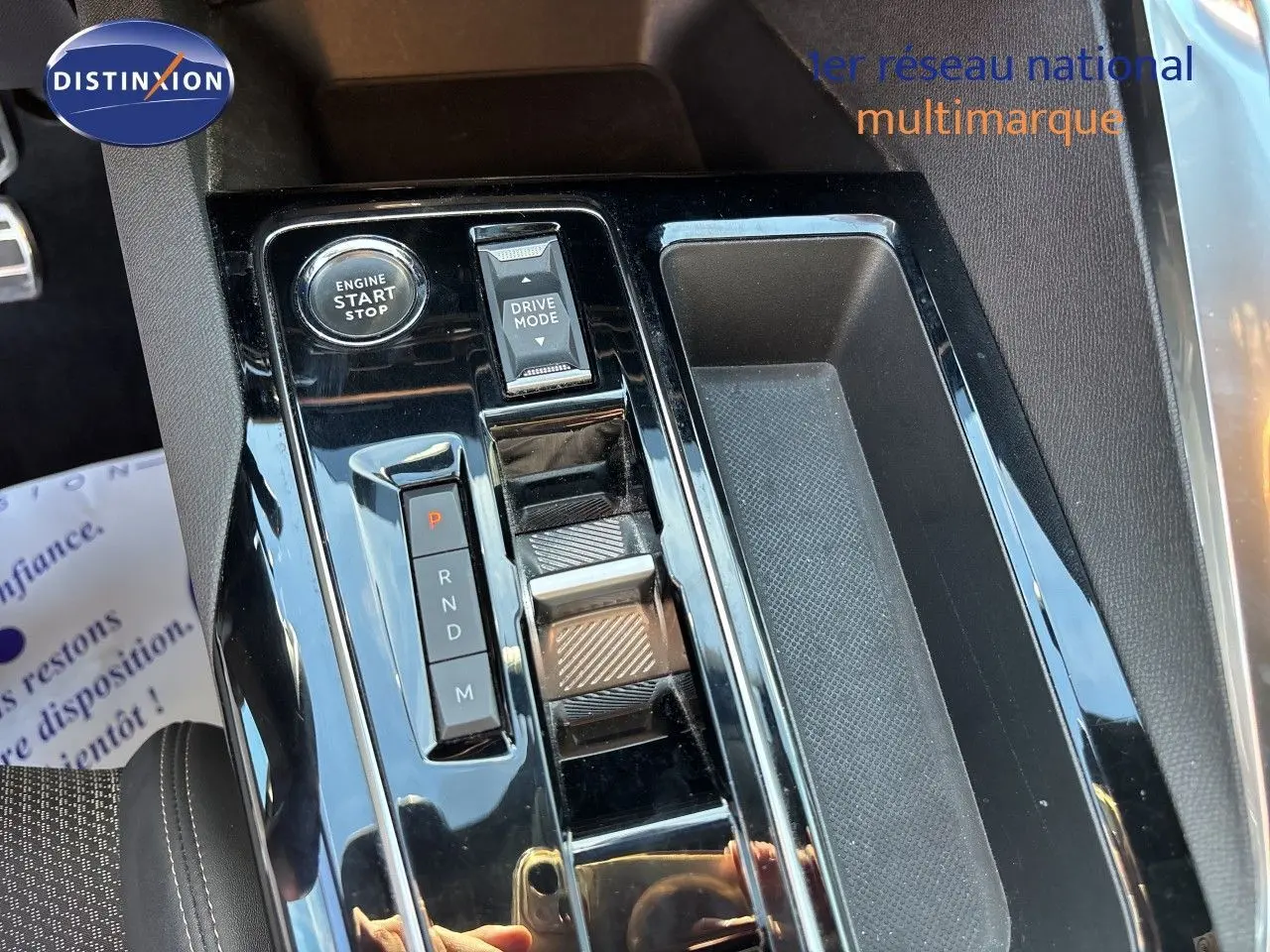 Vue rapprochée de la console centrale noire brillante du Peugeot 5008 GT 2023, avec sélecteur de boîte auto et bouton start.