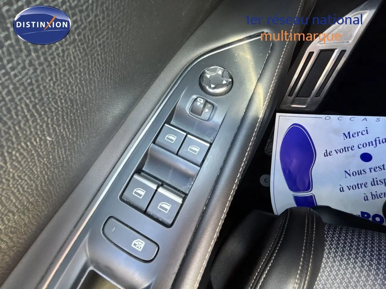 Gros plan sur la commande des vitres côté gauche d’un Peugeot 5008 blanc nacré, avec surpiqûres blanches visibles.