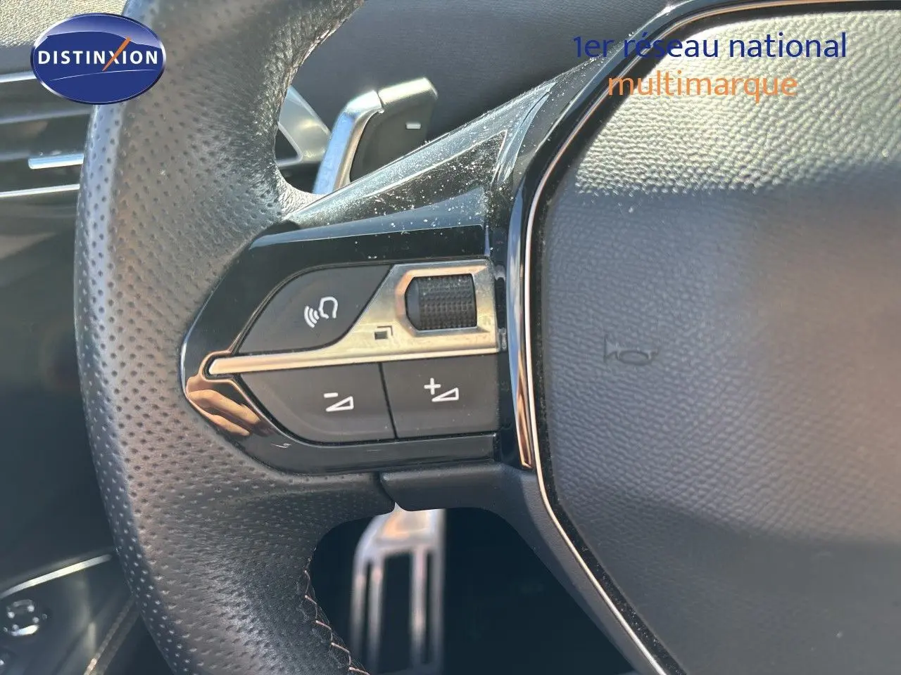 Gros plan sur les commandes au volant en cuir perforé du Peugeot 5008 blanc nacré, version BlueHDi 130 EAT8 GT 2023.