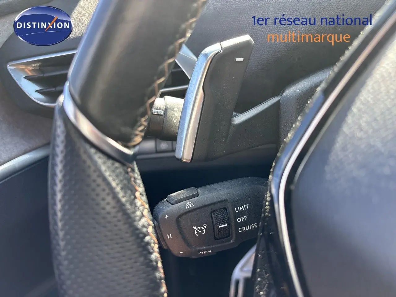 Gros plan sur la commande de régulateur de vitesse derrière le volant d’un Peugeot 5008 blanc nacré 2023.