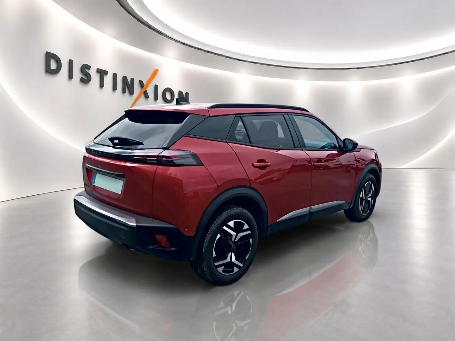 Peugeot 2008 rouge elixir vue 3/4 arrière droit, jantes alu noires et toit noir contrasté en showroom lumineux.