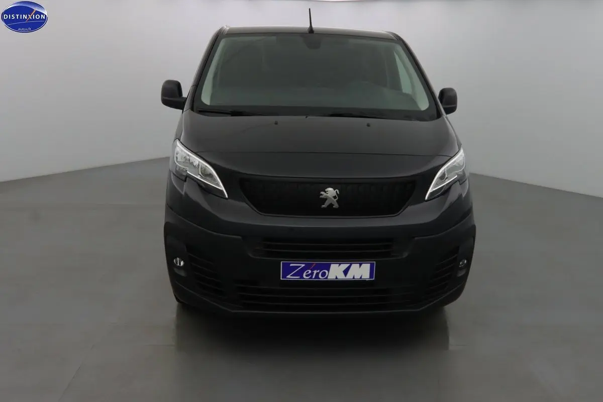 Peugeot Expert Fourgon noir métal vu de face dans un studio, avec logo lion et plaque Zero KM visible.