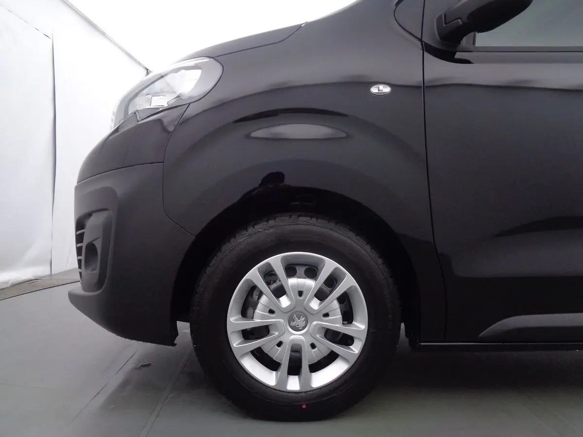 Gros plan sur la roue avant gauche d'un Peugeot Expert Fourgon noir métal 2022, avec jante argentée et logo Peugeot visible.