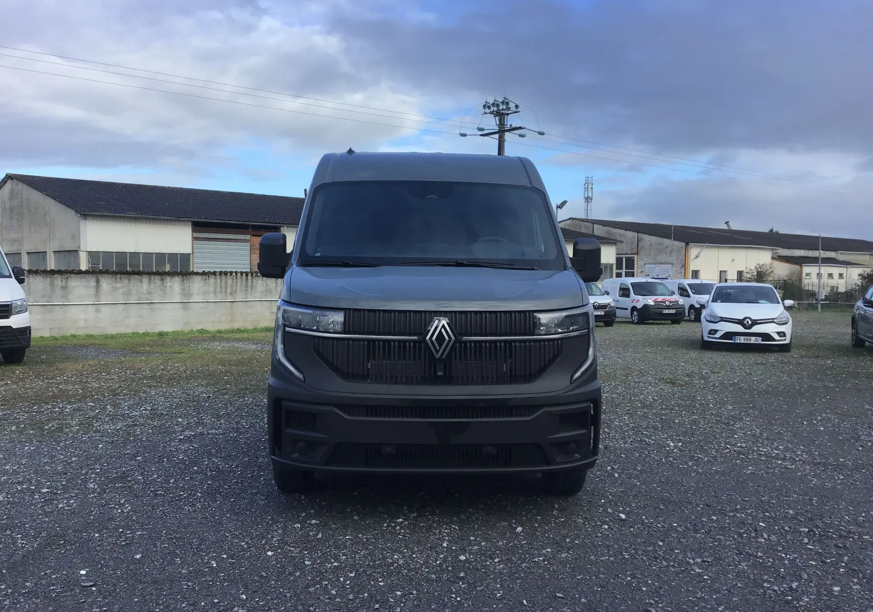 Vue frontale d’un Renault Master L3H2 2025 gris urbain avec calandre noire et logo Renault central sur un parking extérieur.