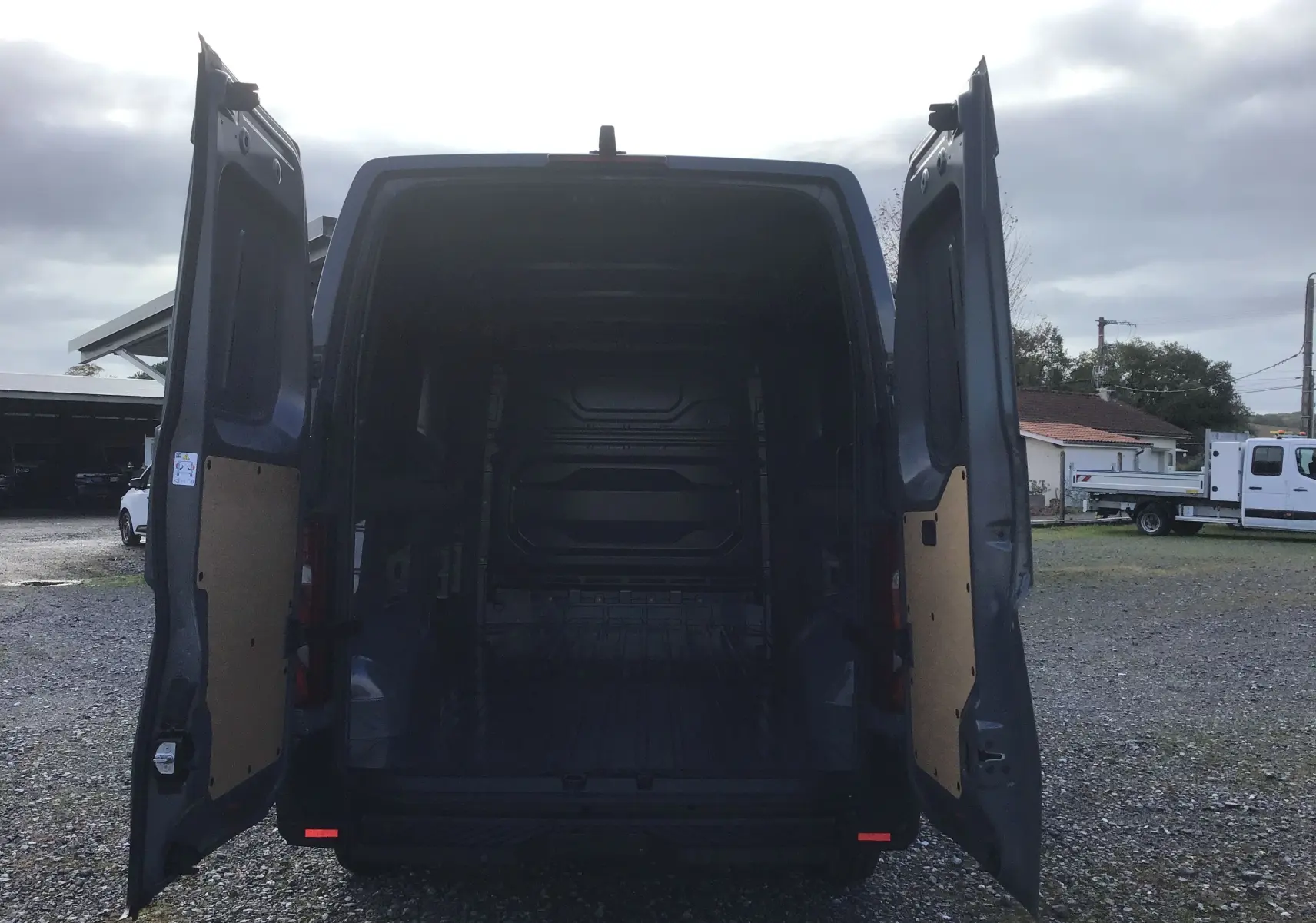 Vue arrière du Renault Master L3H2 gris urbain 2025 avec portes arrière ouvertes montrant l'espace de chargement vide.