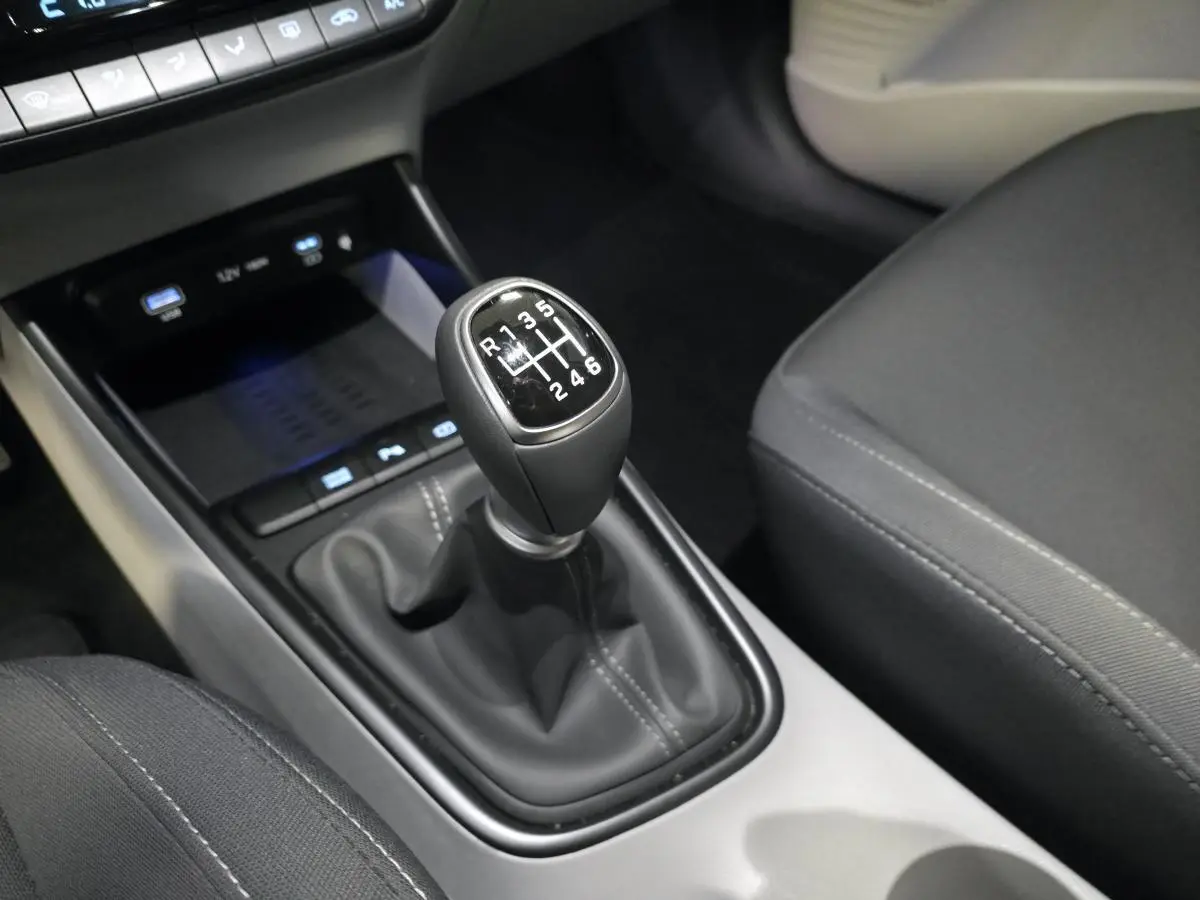 Le levier de vitesses manuel noir du Hyundai BAYON 2025 vu en gros plan côté conducteur avec console grise et sièges foncés.