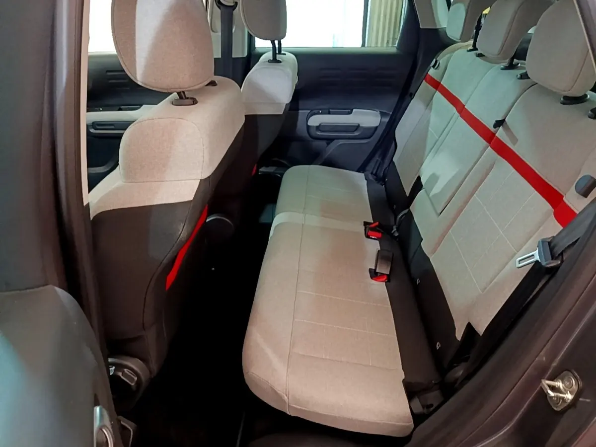 Vue intérieure arrière droite du Citroën C3 Aircross 2020, sièges gris clair avec bande rouge distinctive et ceintures noires.