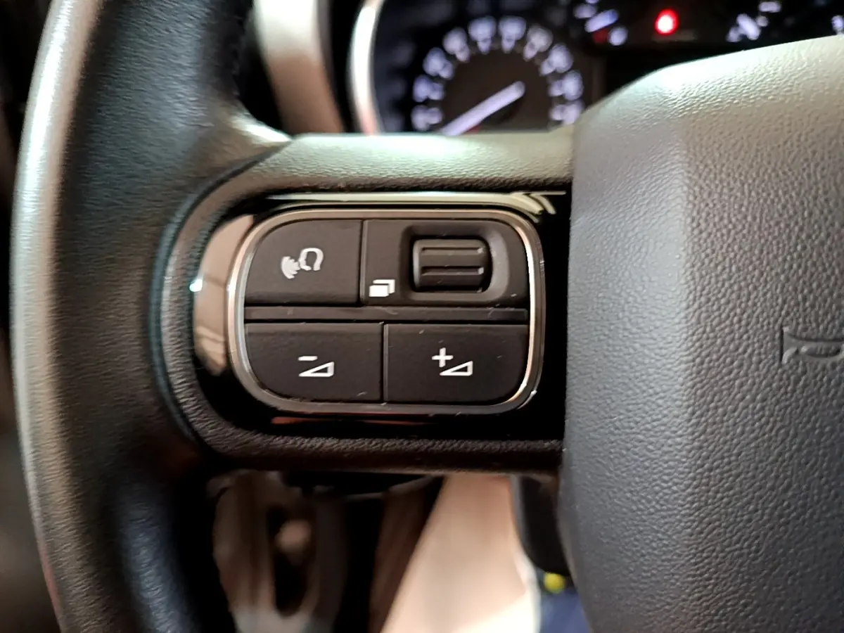 Gros plan sur les commandes multifonctions noires du volant cuir d'une Citroën C3 Aircross 2020.