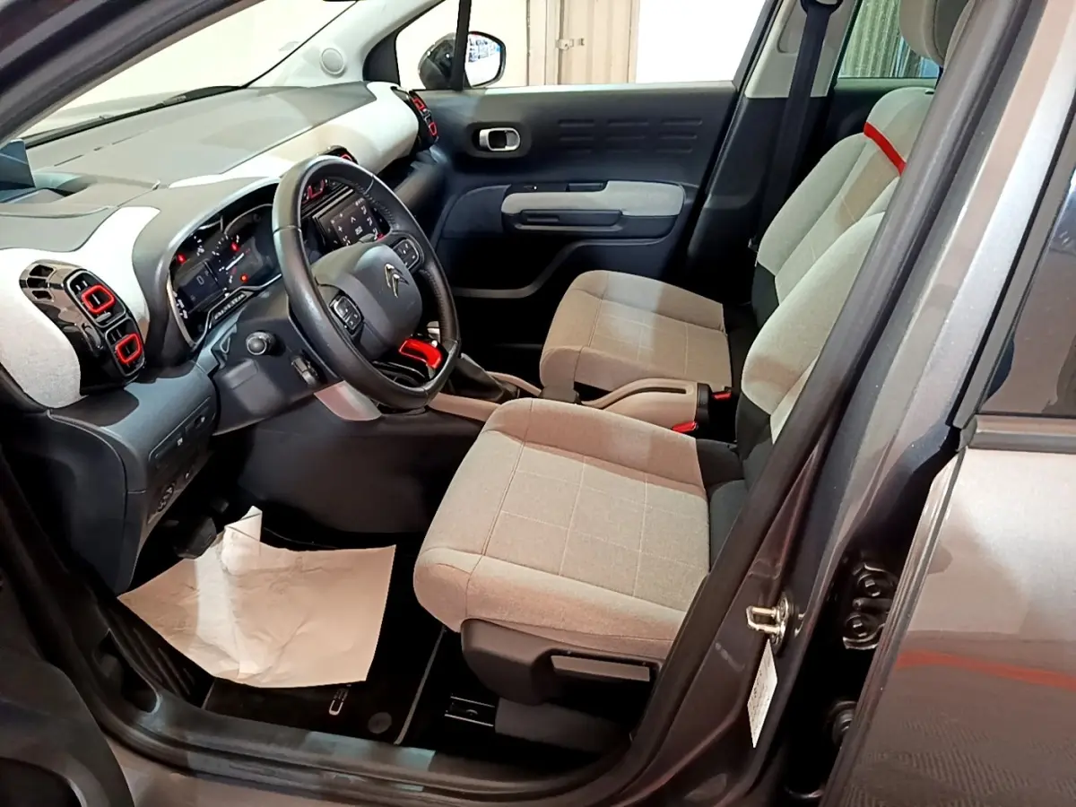 Intérieur avant droit d'une Citroën C3 Aircross 2020 avec sièges gris clair et touches rouges sur la console et aérateurs.