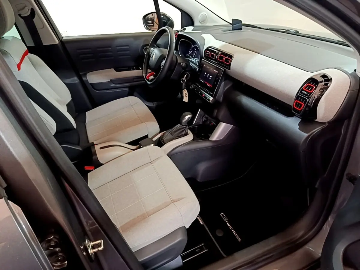 Intérieur avant droit du Citroën C3 Aircross 2020 avec sièges gris clair et tableau de bord clair aux aérateurs rouges.