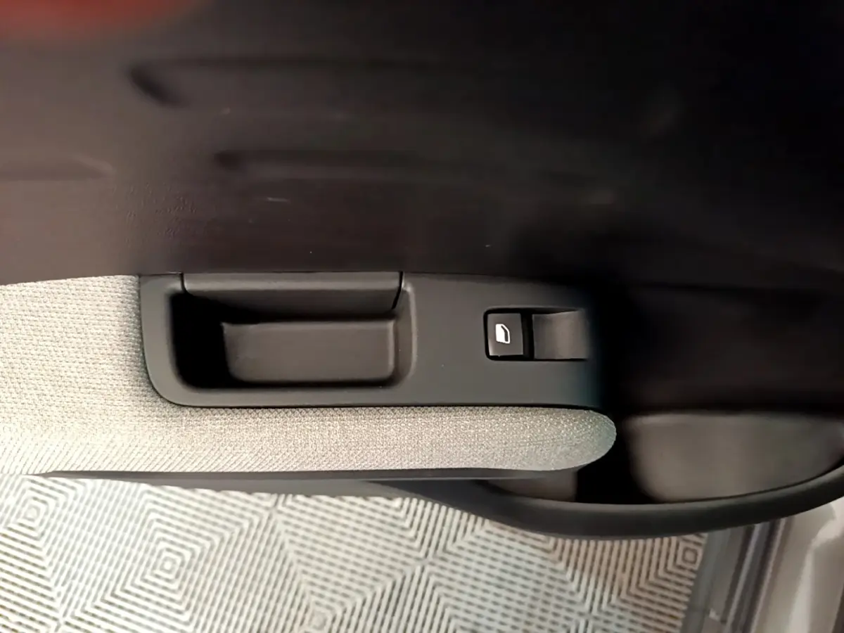 Poignée intérieure et bouton de lève-vitre sur la porte côté droit d'une Citroën C3 Aircross 2020 gris clair.
