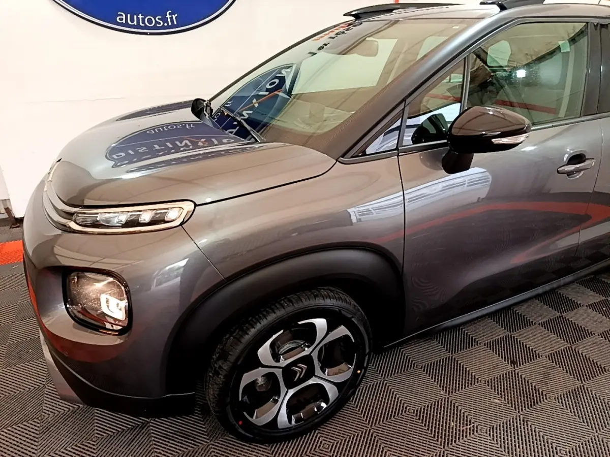 Vue 3/4 avant droit d'un Citroën C3 Aircross gris métallisé avec jantes distinctives et rétroviseurs ton caisse.