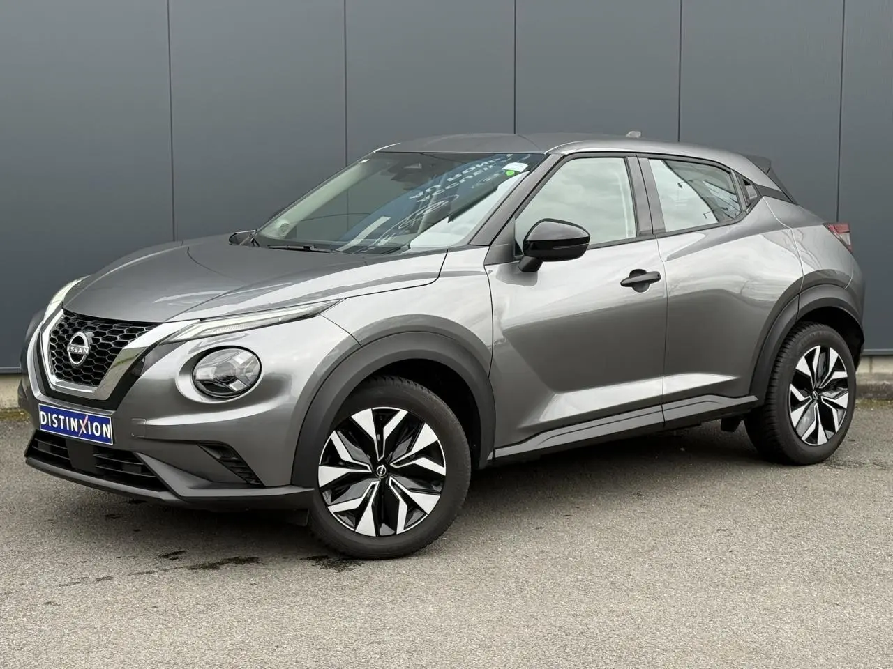 Nissan Juke 2025 gris foncé en vue 3/4 avant droit, avec jantes alliage et calandre distinctive chromée.