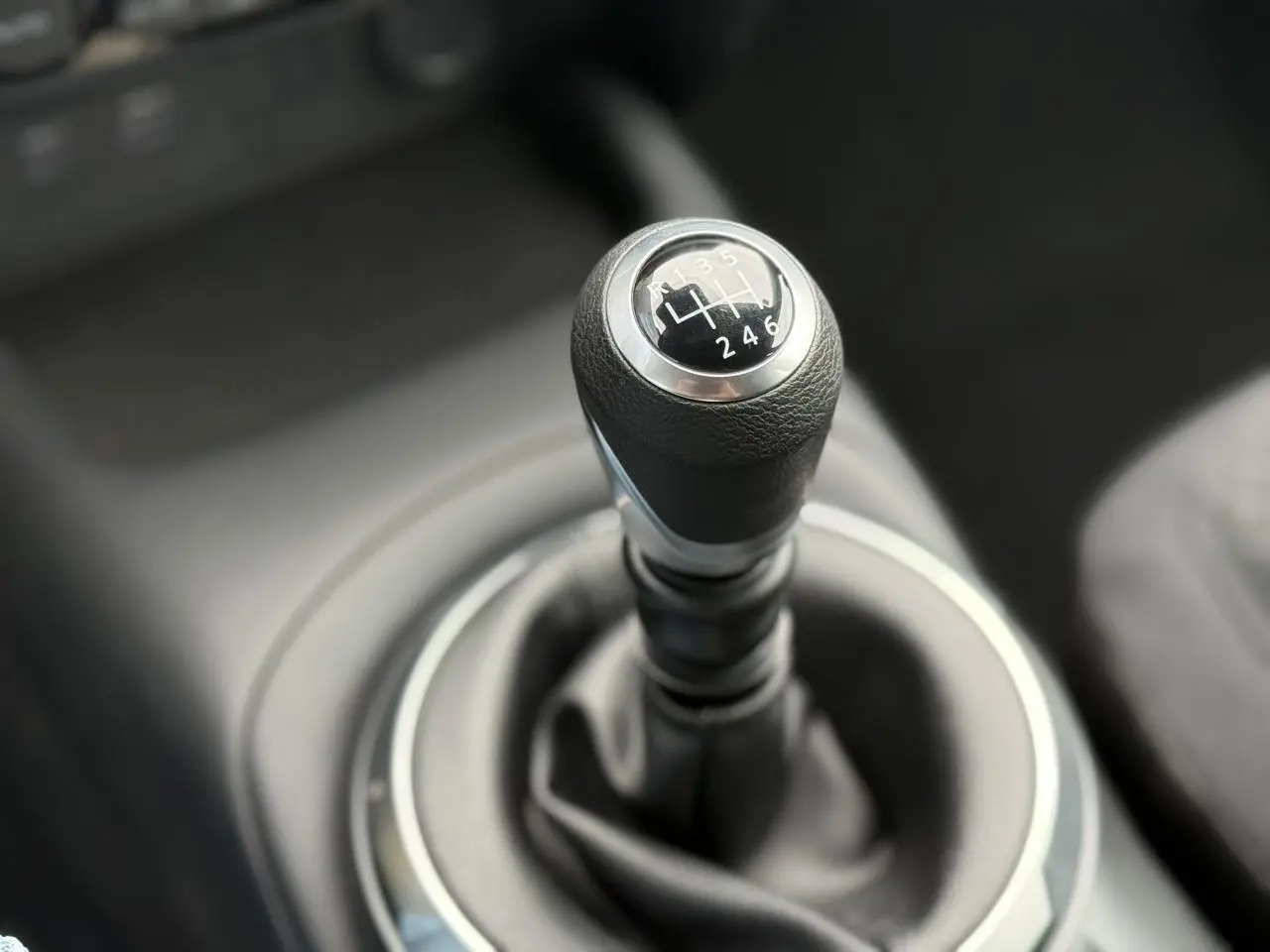 Gros plan sur le levier de vitesses manuel noir du Nissan Juke 2025, finition Acenta, intérieur sombre.