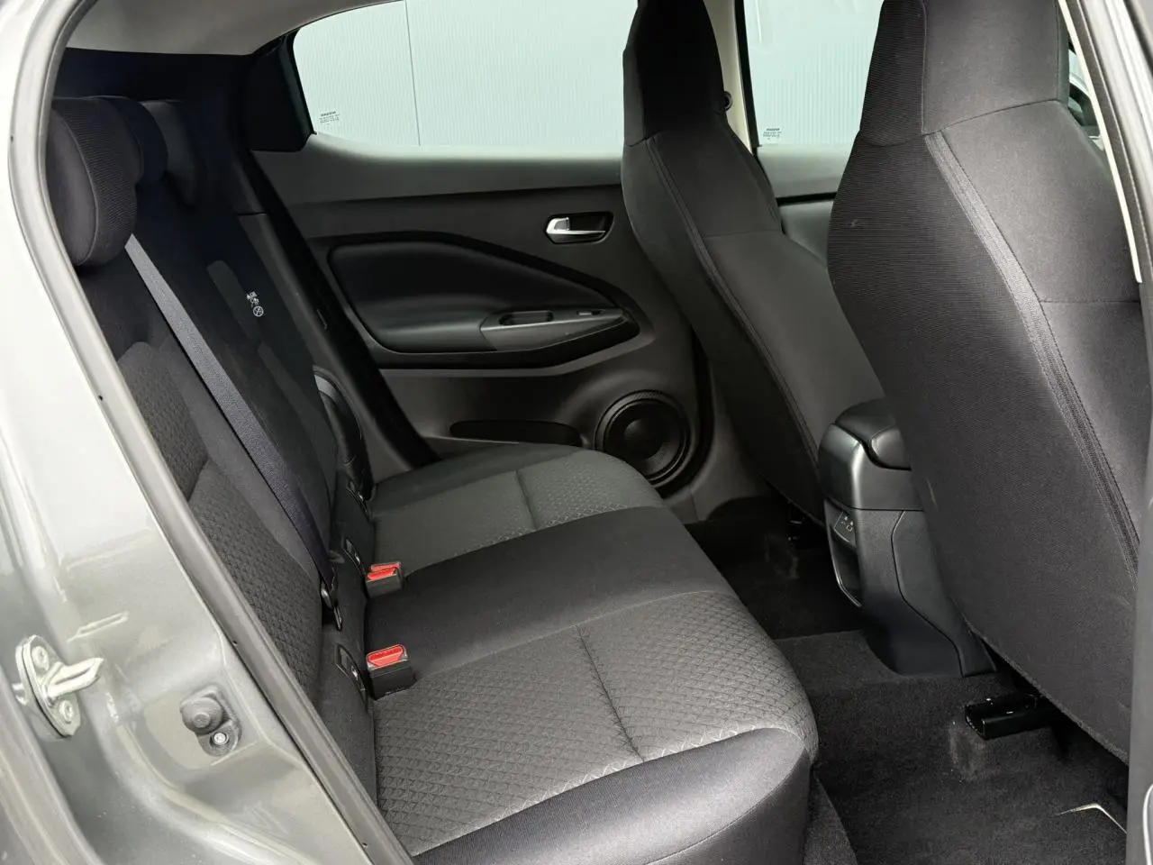 Vue intérieure côté gauche sur la banquette arrière et les sièges avant du Nissan Juke gris foncé 2025.