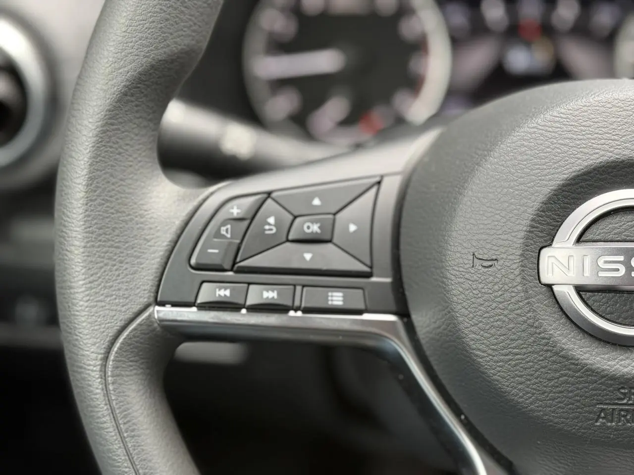 Gros plan sur le volant noir du Nissan Juke 2025, mettant en valeur les commandes multifonctions à gauche.