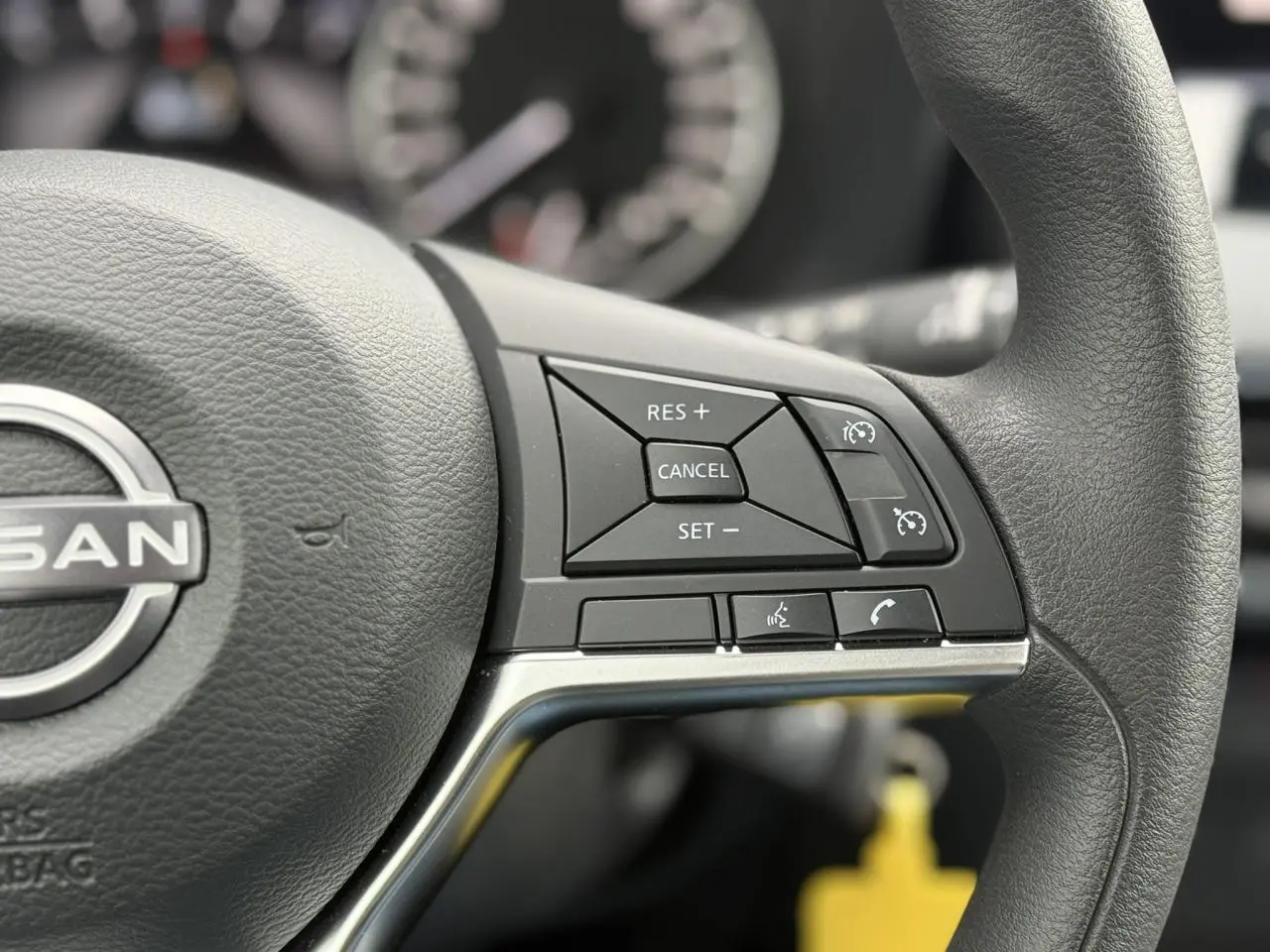 Gros plan sur le côté droit du volant noir du Nissan Juke 2025 avec commandes de régulateur et téléphone.