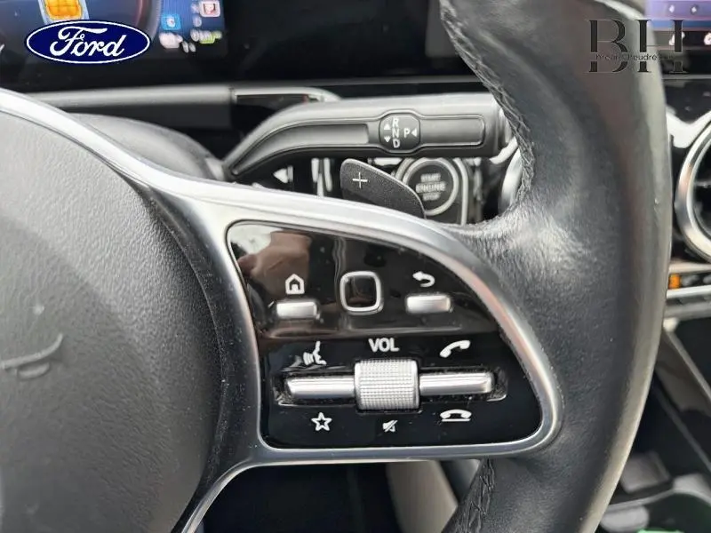 Gros plan sur les commandes au volant cuir noir de la Mercedes Classe B 250 e, avec palettes de changement de vitesse visibles.