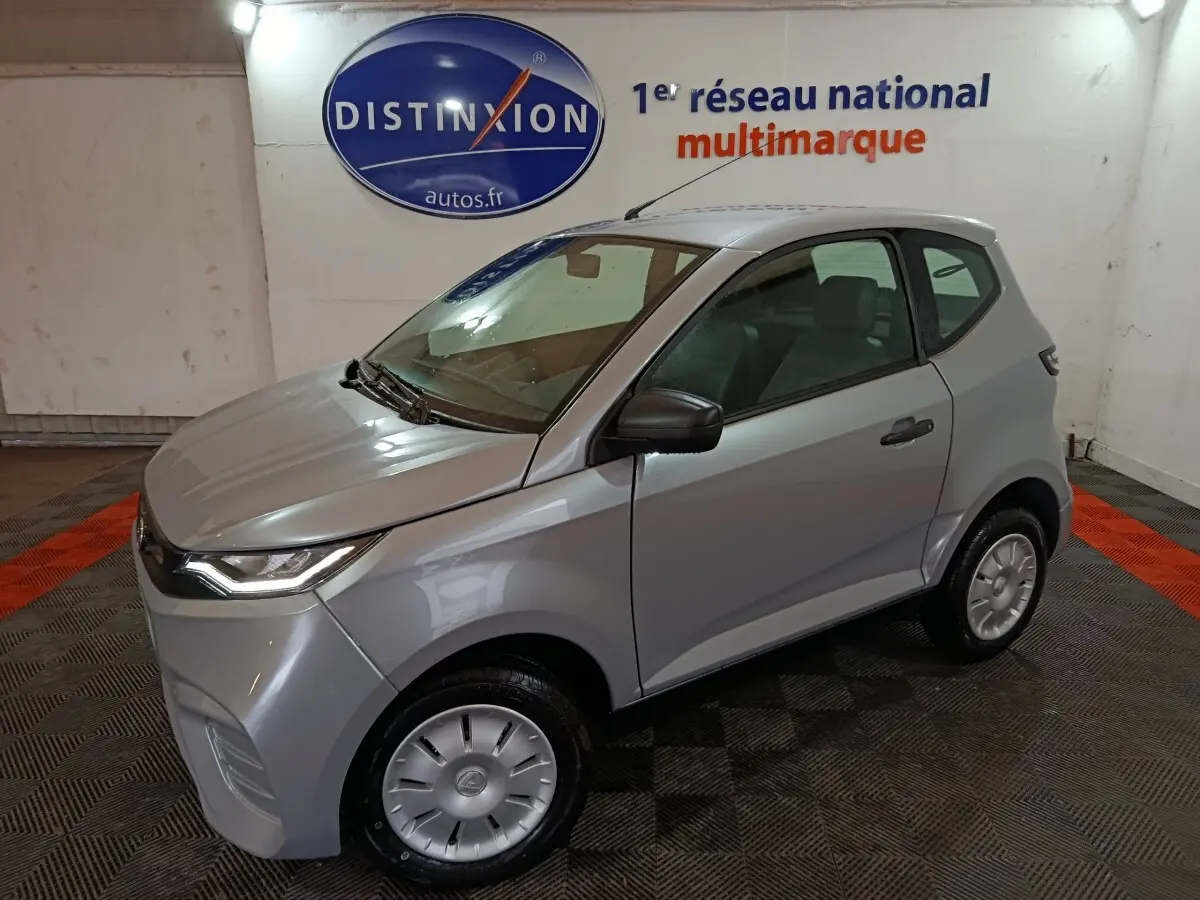 Aixam Ambition 0.5 City Pack gris clair en 3/4 avant droit, avec rétroviseur caméra côté conducteur visible.