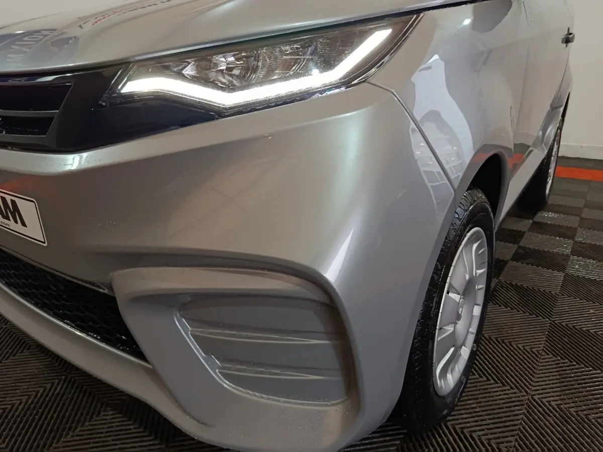 Vue 3/4 avant droit d'une Aixam Ambition 0.5 City Pack gris clair avec phares LED et jantes spécifiques.