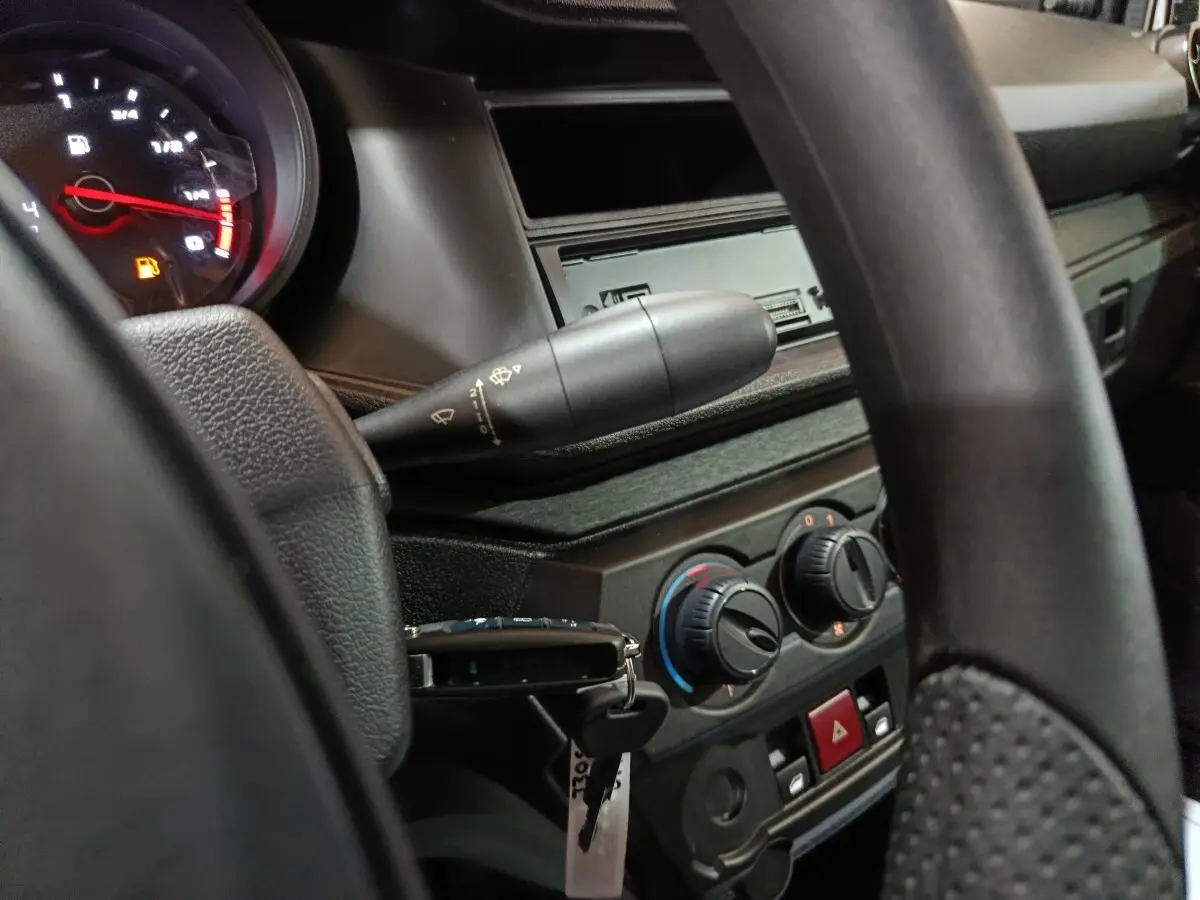 Vue intérieure rapprochée du tableau de bord et volant de l'AIXAM AMBITION 0.5 CITY PACK gris clair, avec commandes de climatisation visibles.