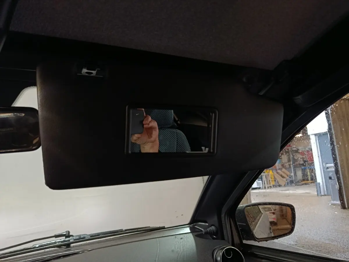 Vue intérieure côté conducteur de l'AIXAM Ambition gris clair 2026, avec pare-soleil et rétroviseur extérieur caméra visible.