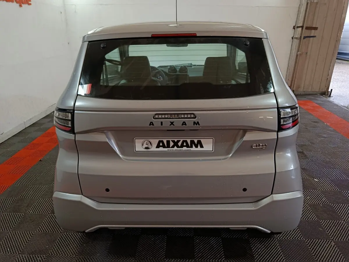 Vue arrière d'une Aixam Ambition 0.5 City Pack gris clair 2026 avec logo et feux arrière modernes.