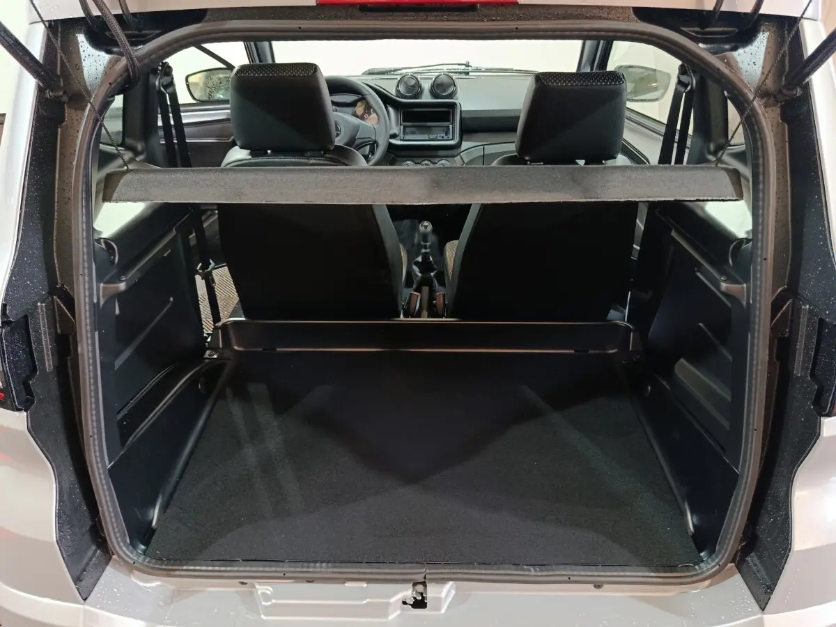 Vue arrière ouverte sur le coffre et l'intérieur de l'AIXAM Ambition gris clair 2026 avec tableau de bord et sièges noirs visibles.