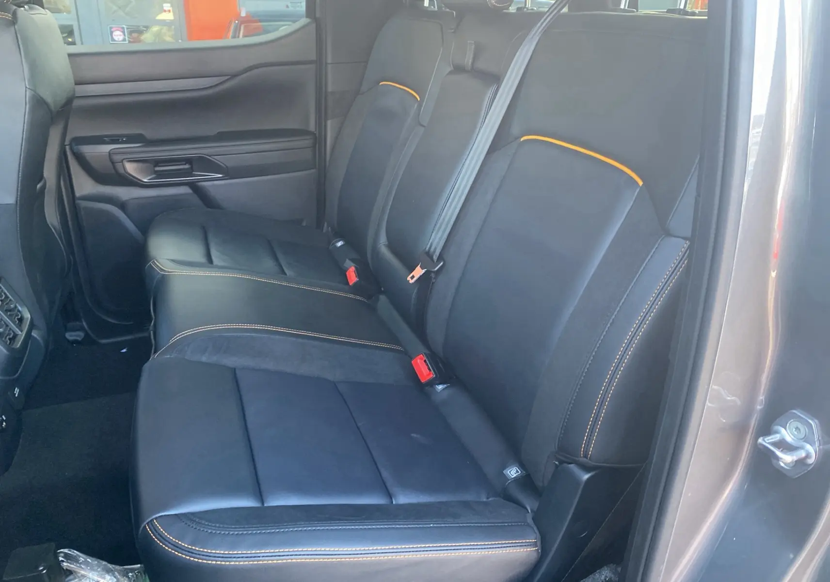 Vue intérieure côté droit sur la banquette arrière cuir noire avec surpiqûres orange du Ford Ranger gris carbone 2026.
