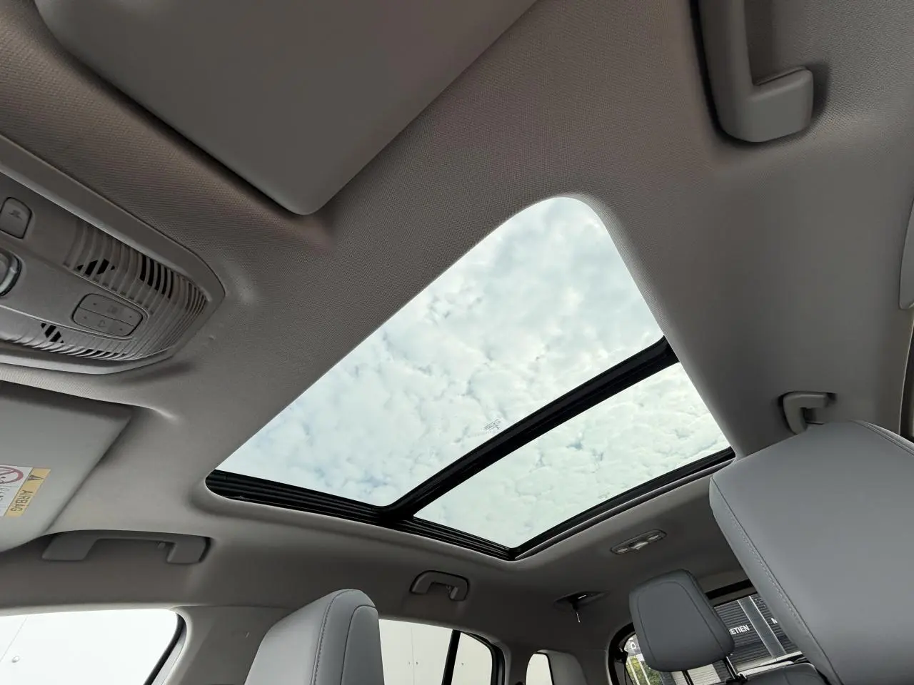 Vue intérieure du toit ouvrant panoramique vitré du Citroën C5 Aircross gris métal avec sièges avant clairs visibles.