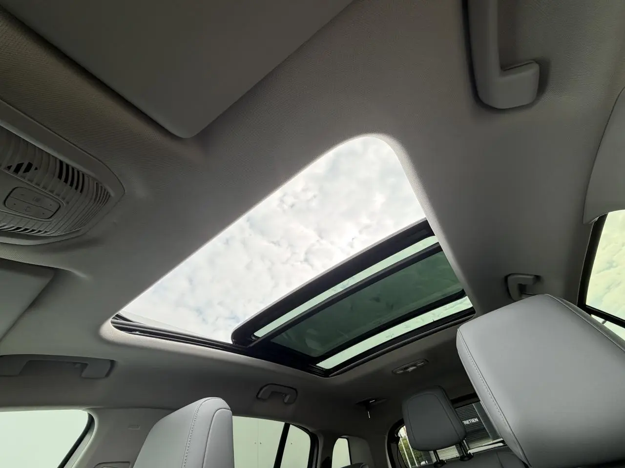 Vue intérieure du toit ouvrant panoramique vitré du Citroën C5 Aircross gris métal 2024, avec sièges avant visibles.