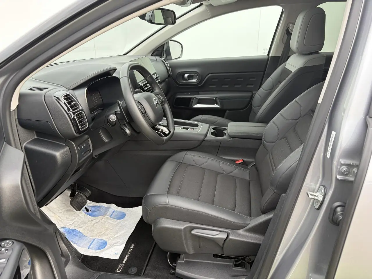 Vue intérieure côté conducteur du Citroën C5 Aircross gris métal 2024, sièges noirs et tableau de bord moderne.