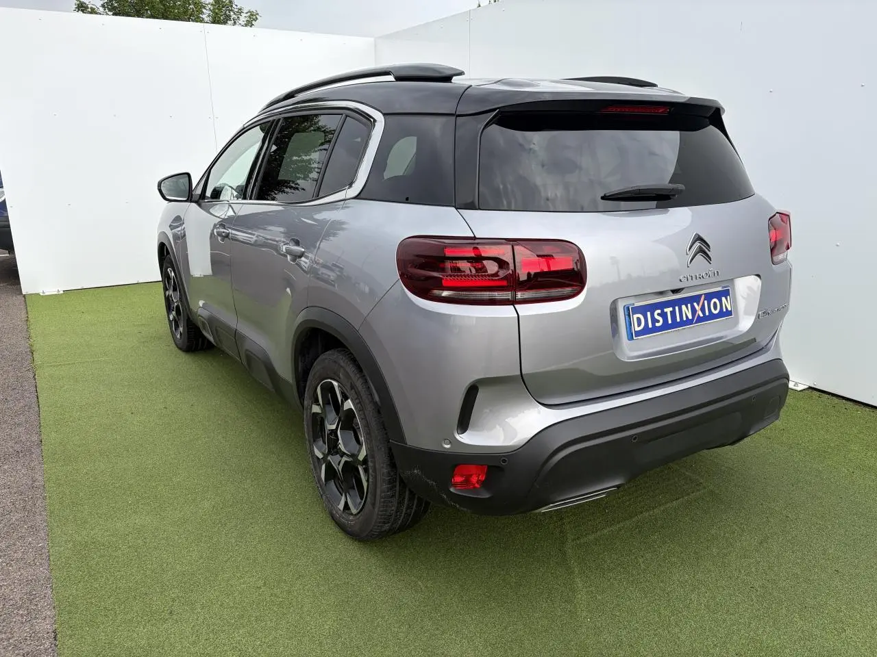 Vue 3/4 arrière droit d'un Citroën C5 Aircross gris métal avec toit noir et jantes bi-ton 18 pouces.