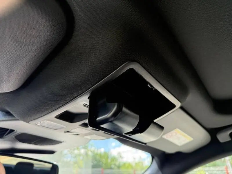 Détail du rangement lunettes ouvert sur le plafond intérieur d’un Ford Kuga noir Agate Métallisée, vue avant.