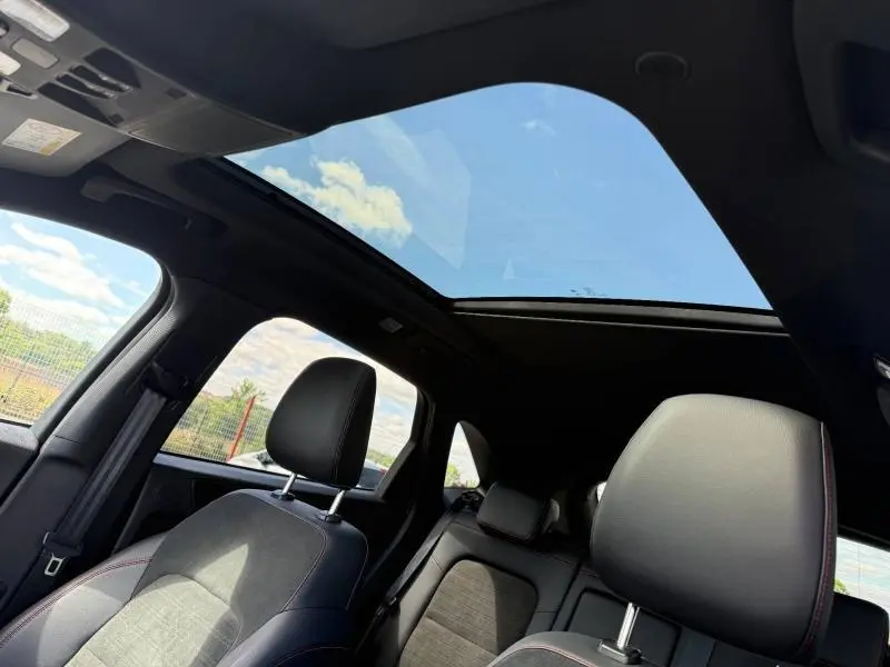 Vue intérieure du Ford Kuga 2023 noir Agate, mettant en valeur le toit panoramique et les sièges sport en cuir noir.