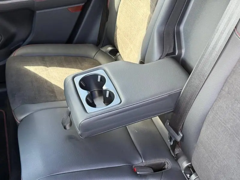 Vue rapprochée de l'accoudoir central arrière en cuir noir avec porte-gobelets du Ford Kuga 2023, sièges en tissu et simili cuir.