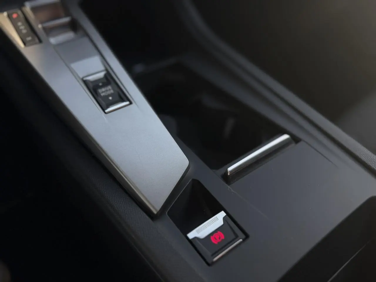 Gros plan sur la console centrale noire de la Peugeot 308 2025, mettant en valeur le frein de parking électrique.
