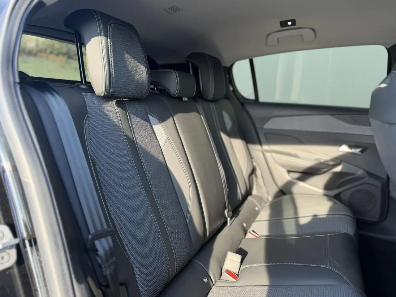 Vue intérieure des sièges arrière en cuir et tissu gris foncé de la Peugeot 308 2025, côté droit ouvert.