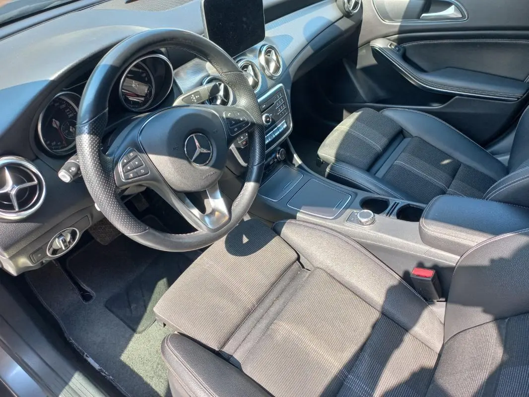 Intérieur de la Mercedes GLA 2019 vue côté conducteur, volant multifonction et sièges tissu gris en lumière naturelle.