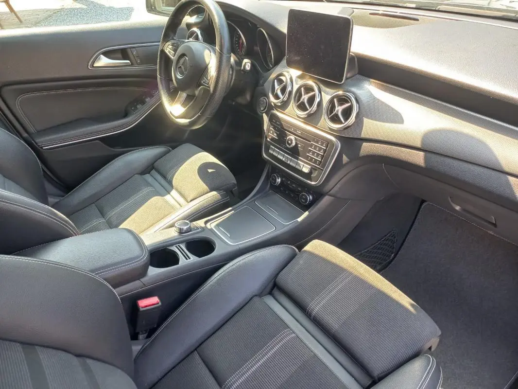 Vue intérieure côté conducteur du Mercedes GLA 2019 gris, avec tableau de bord moderne et sièges en tissu noir.