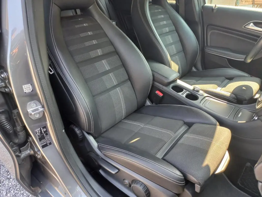 Vue intérieure côté conducteur du Mercedes GLA gris 2019, mettant en valeur les sièges en tissu et cuir avec surpiqûres blanches.