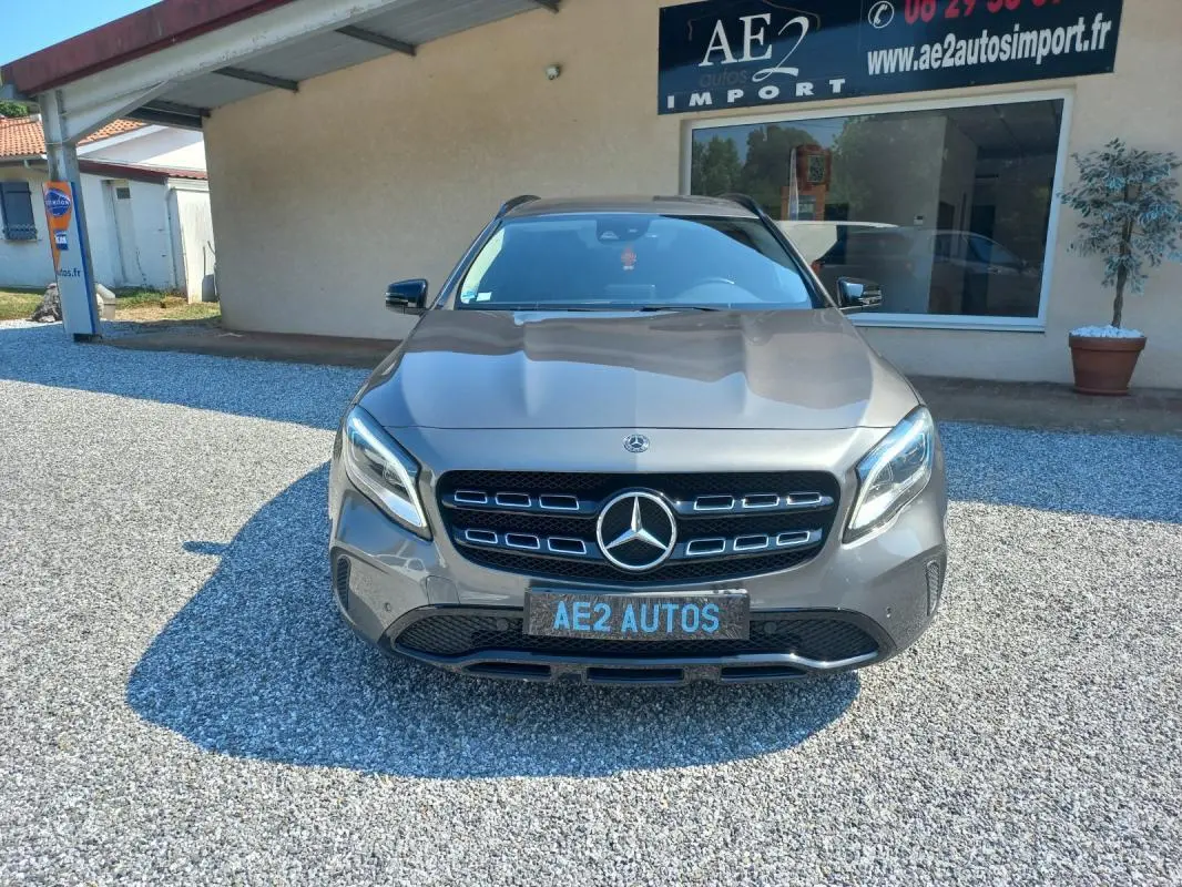 Mercedes GLA gris vue de face, mettant en valeur la calandre distinctive et les phares LED, stationné devant un bâtiment.