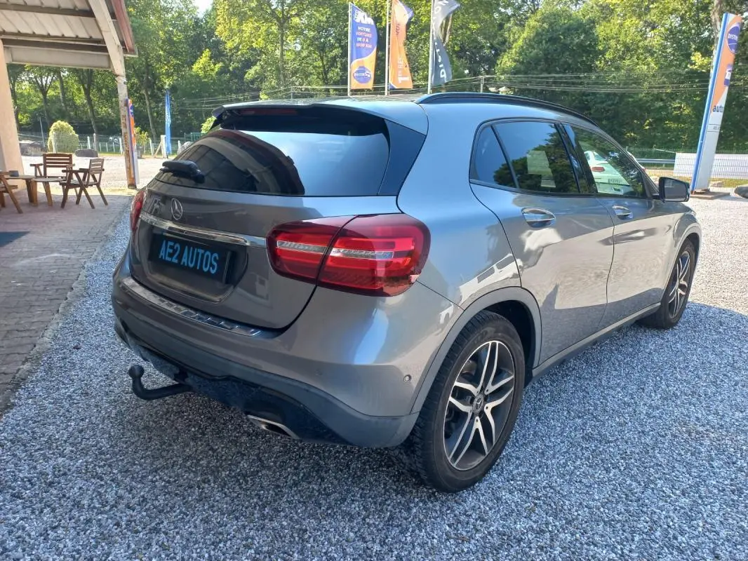 Mercedes GLA gris en 3/4 arrière droit, avec attelage et jantes alliage, stationné sur gravier en extérieur.